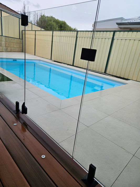 Frameless glass pool fence installed in a Perth backyard with black base-mount spigots - Click Fencing