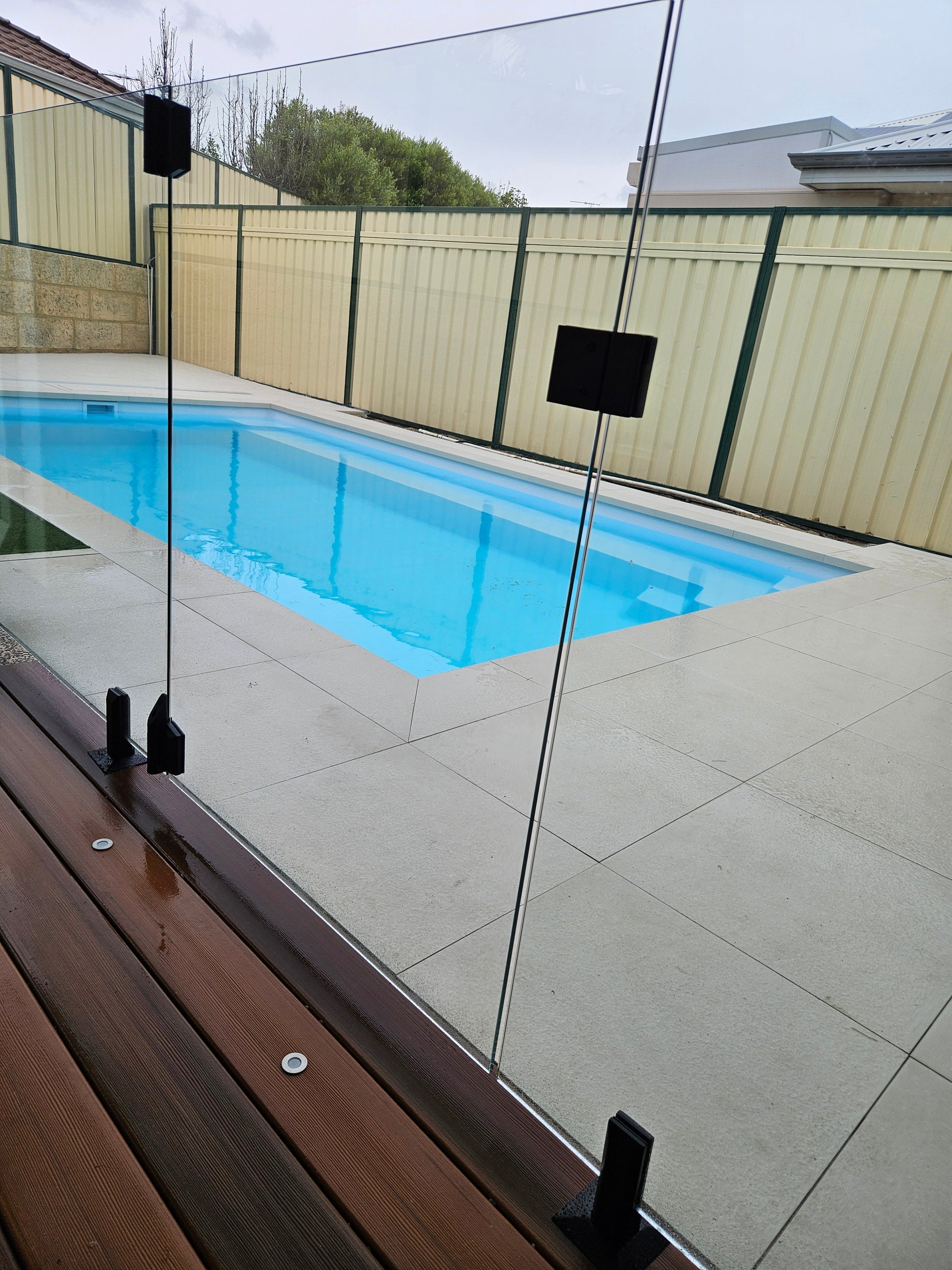 Frameless glass pool fence installed in a Perth backyard with black base-mount spigots - Click Fencing