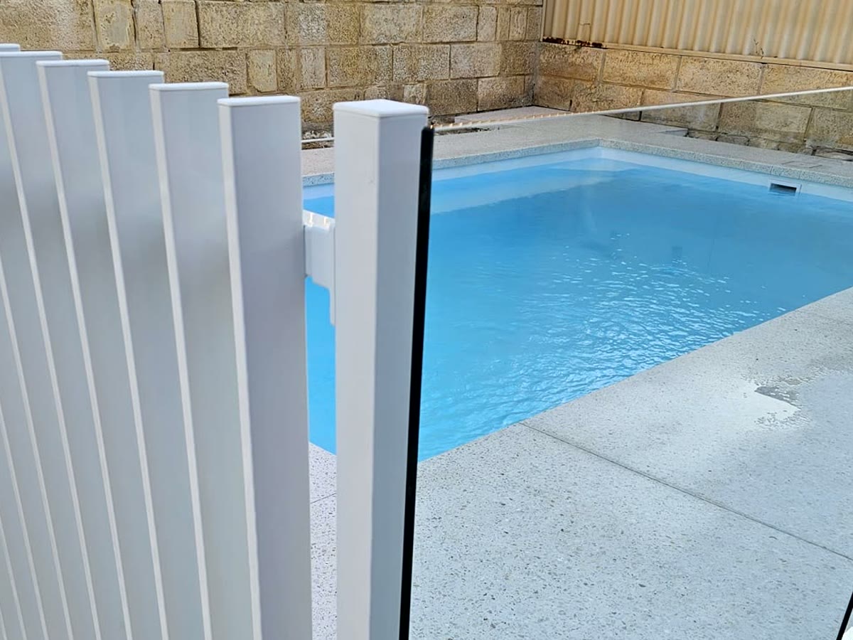 Close-up of a white blade pool fence meeting frameless glass on one Perth pool